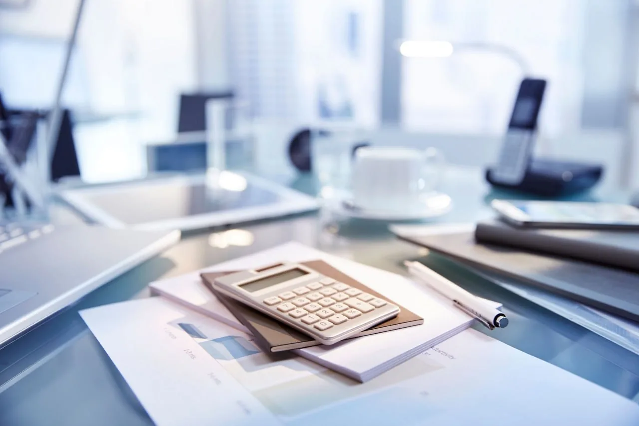 Рабочий стол с калькулятором и бумагами для расчета закупок и поставок